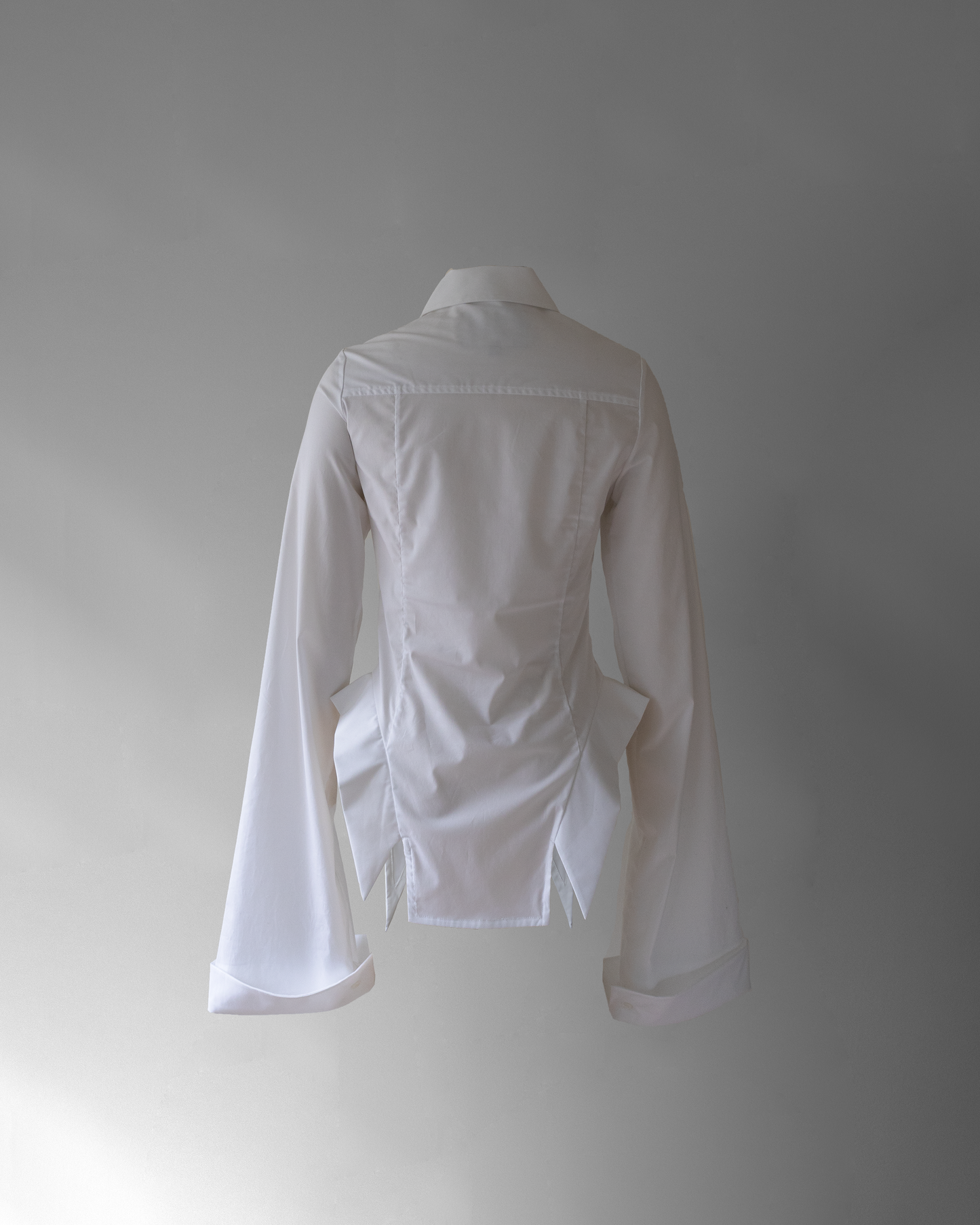 back photo of co11ared blouse, a white blouse with wide long sleeves floating in space on a grey background.